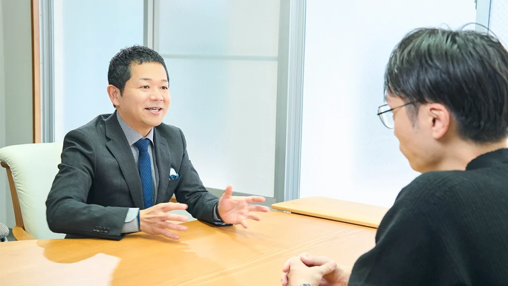 男性スタッフが笑顔でお客様に対して話をしている。