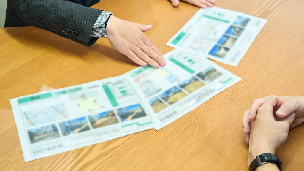 男性スタッフが複数の物件の資料を机に広げて手を添えている